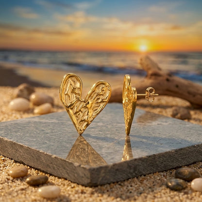 Boucles d'oreilles cœur martelé acier inoxydable 316L doré posées sur fond sable ambiance coucher de soleil - KENVIA