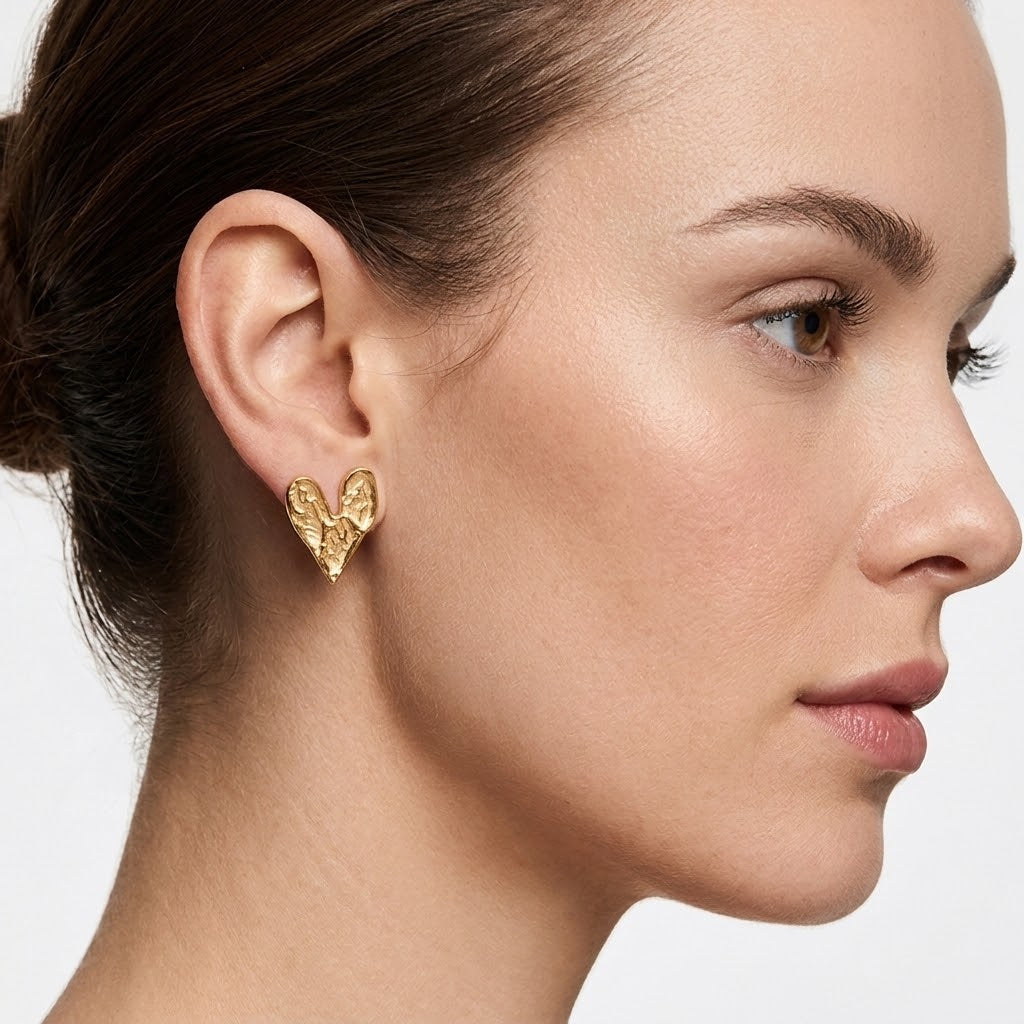 Boucles d'oreilles cœur martelé finition dorée portées par une femme vue de profil élégant - KENVIA