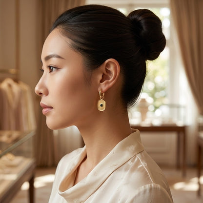 Femme portant les boucles d’oreilles dorées à pendentif et résine bleue - KENVIA