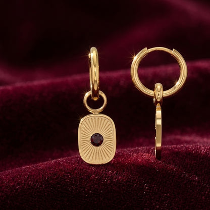 Paire de boucles d’oreilles dorées avec pendentifs striés et résine marron sur fond rouge foncé - KENVA