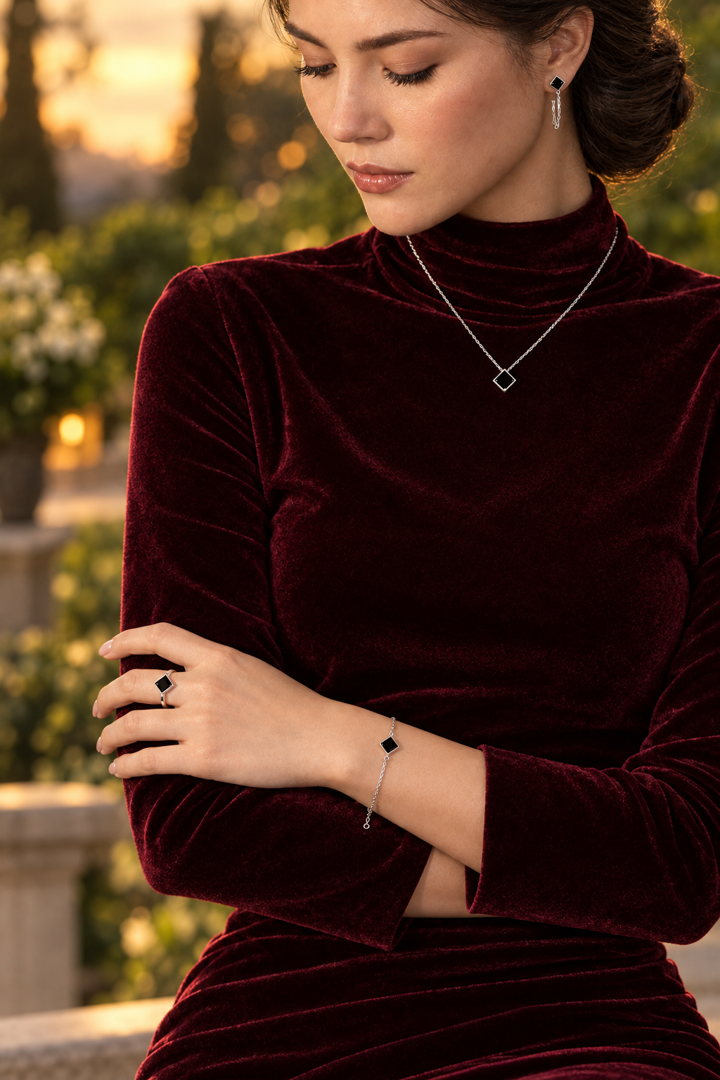 Femme en robe bordeaux portant les boucles d’oreilles à losange noir avec un collier, un bracelet et une bague assortis - KENVIA