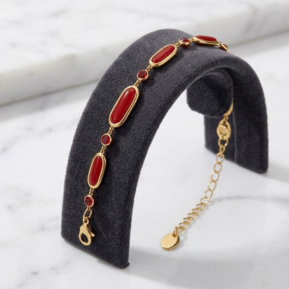 Bracelet en verre rouge et acier inoxydable 316L finition dorée présenté sur un support anthracite - KENVIA