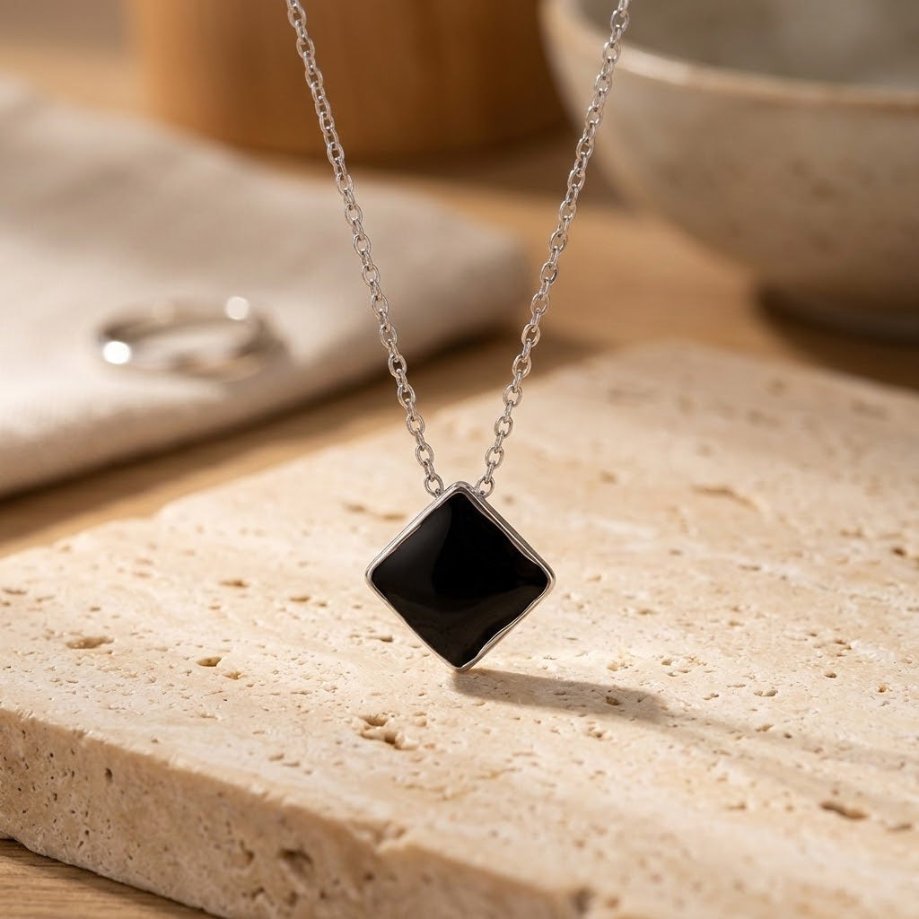 Collier en acier inoxydable 316L avec pendentif losange noir posé sur une surface claire - KENVIA