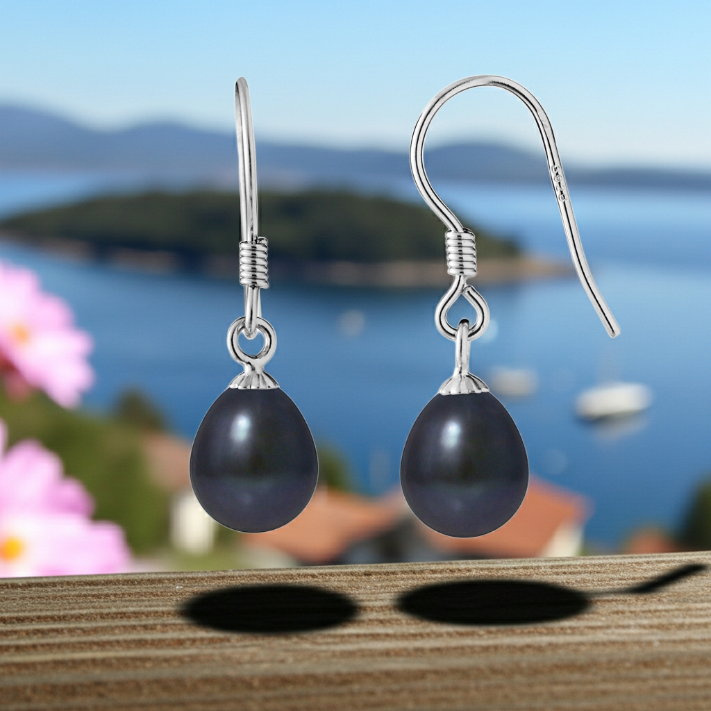 Paire de boucles d'oreilles pendantes perles noires sur fond bleu mer, vue rapprochée