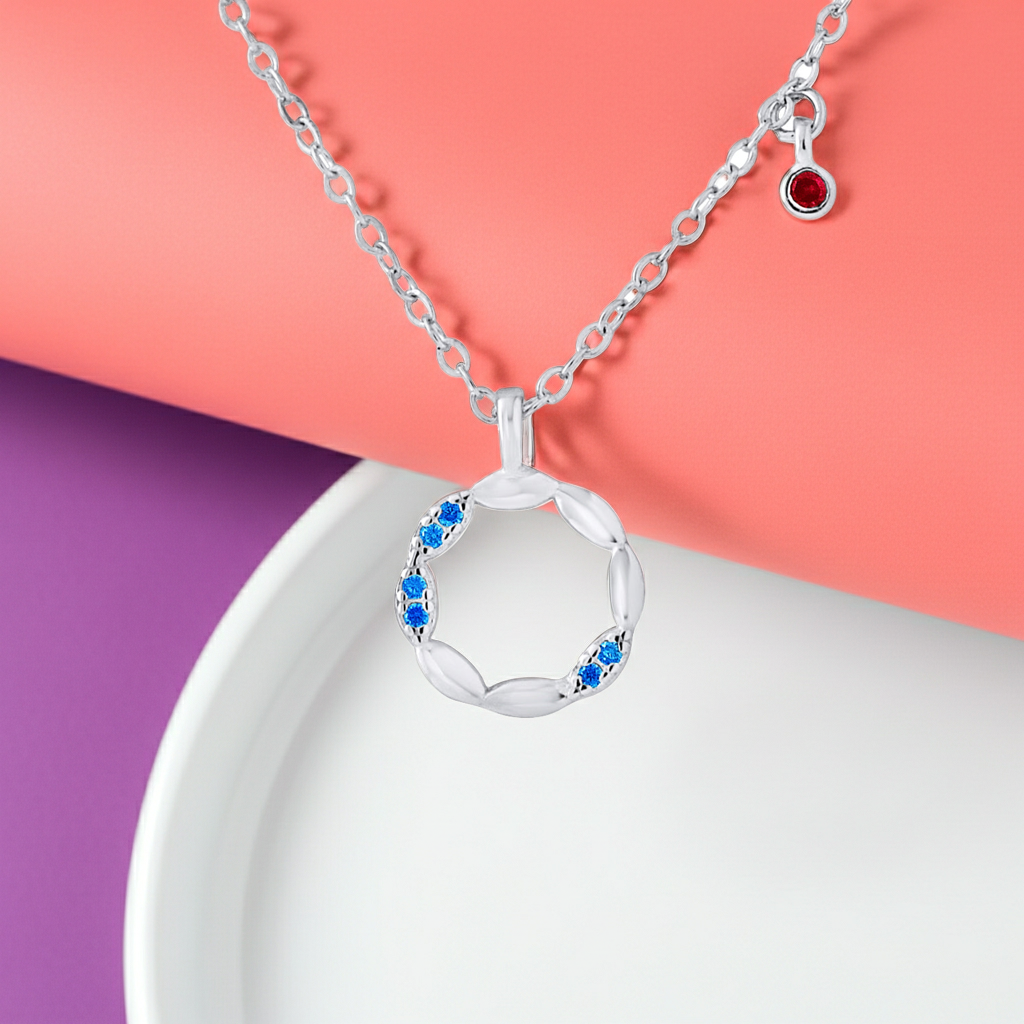 Collier cercle en argent 925 avec zirconium bleu et rouge posé sur fond rose – KENVIA